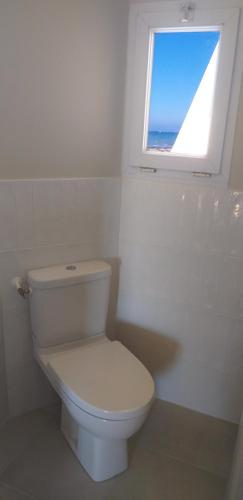 a white toilet in a bathroom with a window at Vue exceptionnelle en front de mer, 8 personnes in Ver-sur-Mer