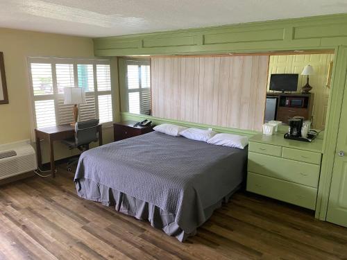 Inn On The Green Florida في تفاريس: غرفة نوم بسرير ومكتب ونوافذ