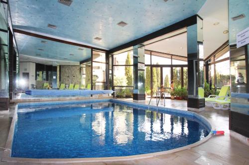 a large swimming pool in a building with windows at Alpine Lodge Bansko Apartments in Bansko