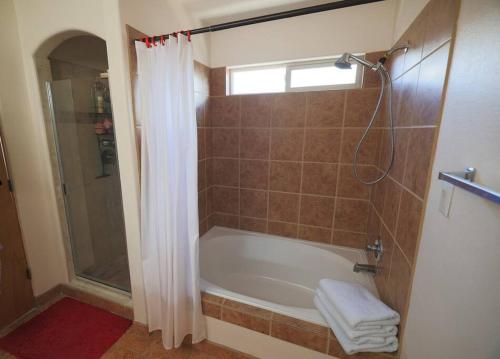 a bathroom with a tub and a shower with a window at Home near Balloon Fiesta Park! in Albuquerque