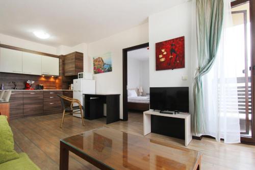 a living room with a couch and a tv and a kitchen at Alpine Lodge Bansko Apartments in Bansko