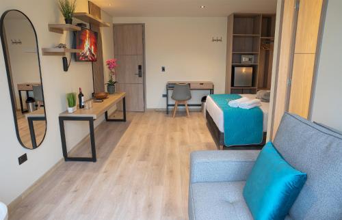 a room with a bed and a desk and a couch at Hotel Fontana Bogotá - Corferias in Bogotá