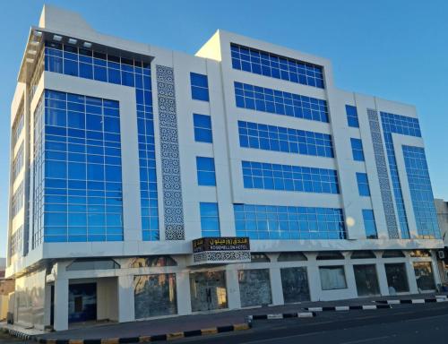 a large building with blue windows on a street at فندق روزميلون in Al Fayşalīyah
