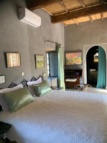 a bedroom with a large white bed with green pillows at RIAD CHANT D'ETOILES tadighoust in El Hara