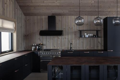 a kitchen with blue cabinets and a stove and lights at Luxurious Mountain Lodge in Ljørdal