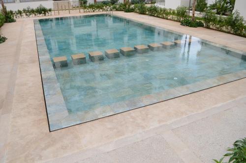 a swimming pool in a building with blue water at New Luxury apartment 5 min Casablanca Mohammed V Airport in Casablanca