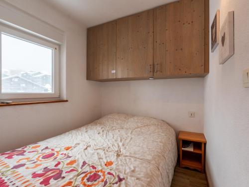 um pequeno quarto com uma cama e armários de madeira em Les Sitelles - 12 - Appt vue montagne - 6 pers em Morillon