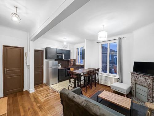 un salon avec un canapé et une cuisine avec une table dans l'établissement Un Coin Tranquille de Bagneux, à Bagneux