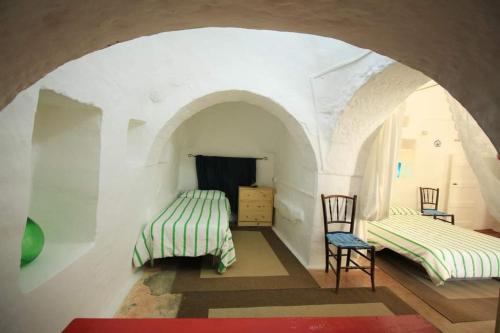 Habitación con 2 camas, mesa y sillas en La valle dei trulli, en Villa Castelli