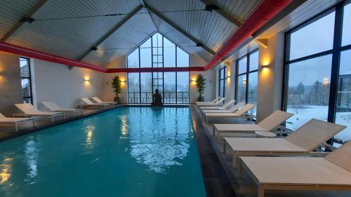 a pool with white chairs and windows at Azur en Ardenne in Durbuy