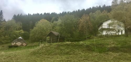 a field with a building and a house on a hill at Les habitats de la chaume in Plainfaing