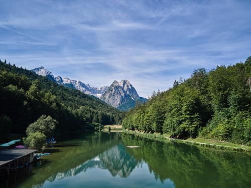 a river with trees and mountains in the background at Riessersee Hotel in Garmisch-Partenkirchen
