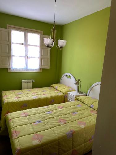 a green room with two beds and a window at Apartamento Las Martas in Comillas