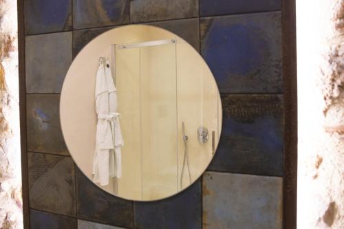 a round mirror on a wall with a towel at PORTA SOPRANA luxury guest House & spa in Sclafani