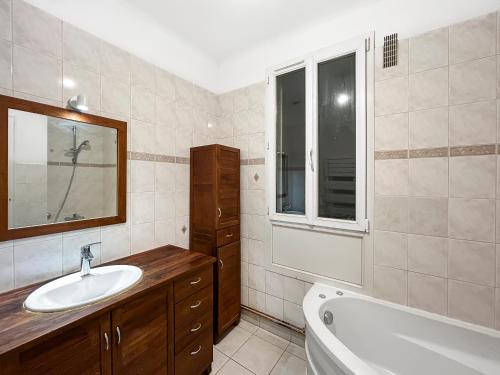 une salle de bain avec un lavabo et une baignoire dans l'établissement Un Coin Tranquille de Bagneux, à Bagneux