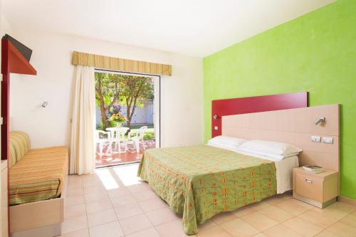 a hotel room with a bed and a balcony at Sibari Green Resort in Marina di Sibari