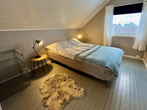 a bedroom with a bed and a lamp and a rug at Panorama Valley Lofoten in Bøstad