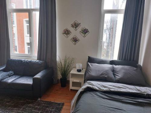 uma cama e um sofá num quarto com janelas em Cosy Studio em Bruxelas