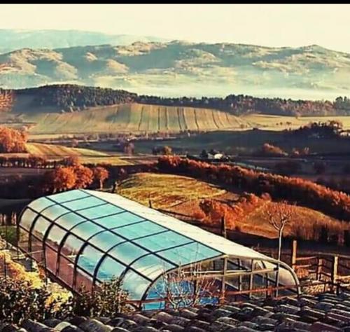 a large greenhouse in a field with mountains in the background at appartamento Colticciola Agriturismo Marche in Cagli