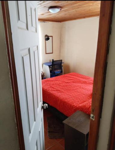 una camera con letto rosso e scrivania di Casa campo camino a pelluhue a De Cauquenes