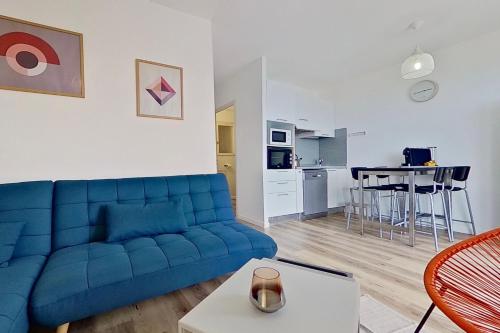 Résidences Sopramare في ألغاجولا: غرفة معيشة مع أريكة زرقاء ومطبخ