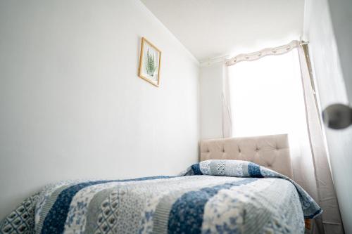 um quarto com uma cama com um cobertor azul e branco em Bonito departamento a pasos del Movistar Arena. em Santiago