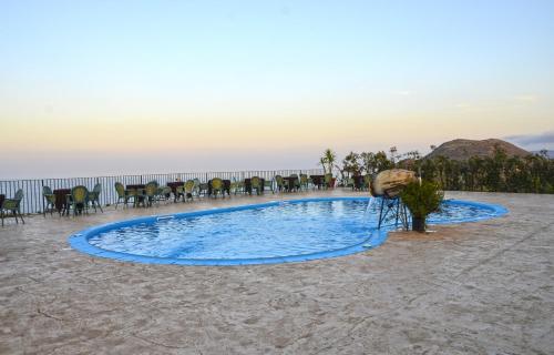 una piscina sulla spiaggia con tavoli e sedie di Eolian Residence a Città di Lipari