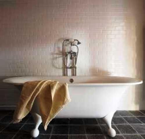 a white bath tub with a towel on it in a bathroom at Hostellerie du Cigalou in Bormes-les-Mimosas