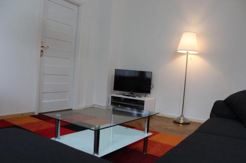 a living room with a glass coffee table and a flat screen tv at Apartments Ålholmvej in Copenhagen