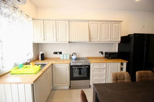 a kitchen with white cabinets and a black refrigerator at Gzira 3 bedroom apartment in Il-Gżira