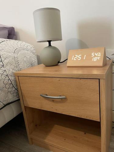 a nightstand with a clock and a lamp on it at Luxury apartment near CDG & Parc Asterix in Vémars