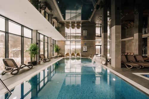 a pool in a building with chairs and a swimming pool at Hotel Saltic Resort & Spa Grzybowo in Kołobrzeg