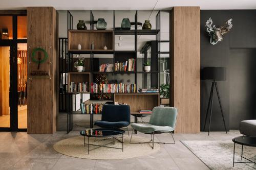 uma sala de estar com duas cadeiras e uma estante de livros com livros em Hotel Saltic Resort & Spa Grzybowo em Colberga