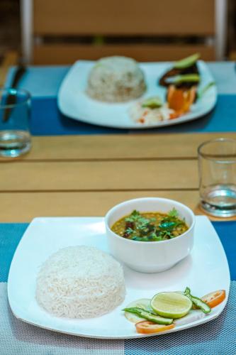 a table with plates of food and a bowl of rice at Maamadi Boutique in Maafushi