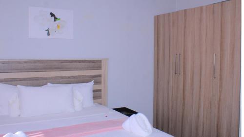 Schlafzimmer mit einem Bett und einem Holzschrank in der Unterkunft Serene Cottage in Francistown