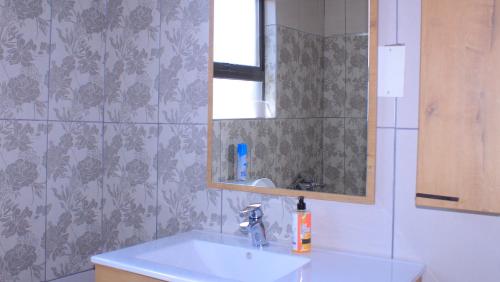 a bathroom with a sink and a mirror at Serene Cottage in Francistown