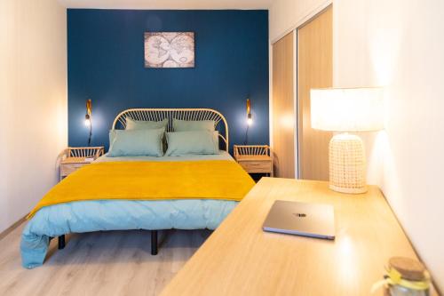 - une chambre avec un lit et un ordinateur portable sur une table dans l'établissement Les Jardins du Pont Rouge - Cosy et Calme, à Aurillac