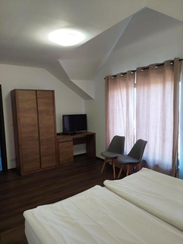 1 dormitorio con 2 sillas, 1 cama y TV en Pensiunea Grandor, en Păltiniş