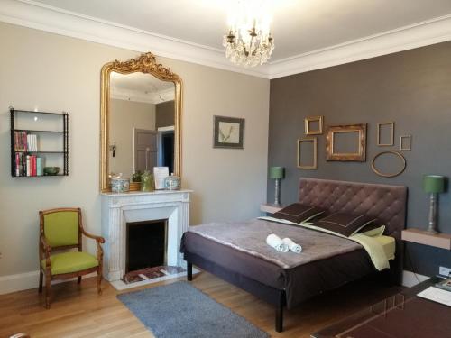 a bedroom with a bed and a mirror and a chair at Chambres d'Hôtes de luxe Côté Parc-Côté Jardin avec parking privé gratuit in Nevers