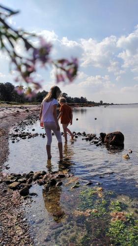 a woman and a child standing in the water at Bright summer house close to the beach and water in Holbæk