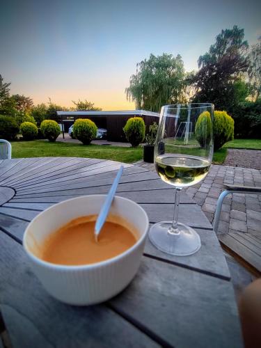 a bowl of soup and a glass of wine on a table at Bright summer house close to the beach and water in Holbæk