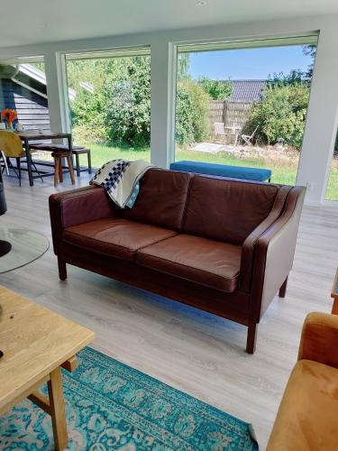 a brown leather couch in a living room at Bright summer house close to the beach and water in Holbæk