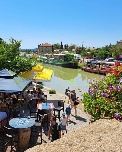 a group of people walking along a river with a boat at Villa Napoléon Piscine&Jacuzzi in Le Somail