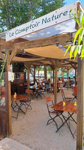 a wooden pavilion with chairs and tables and a sign at Villa Napoléon Piscine&Jacuzzi in Le Somail