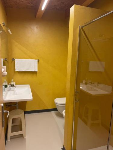 a yellow bathroom with a toilet and a sink at Agritur Anselmi in Terzolas