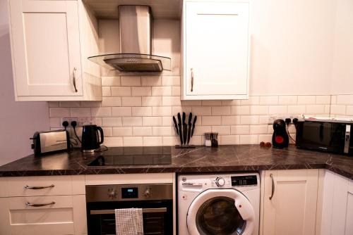 a kitchen with a washing machine in a kitchen at Converted Chapel Swansea | King Bed | Sleeps 4. in Swansea