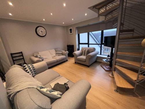 a living room with a couch and a staircase at The Coastal Apartment in Dublin