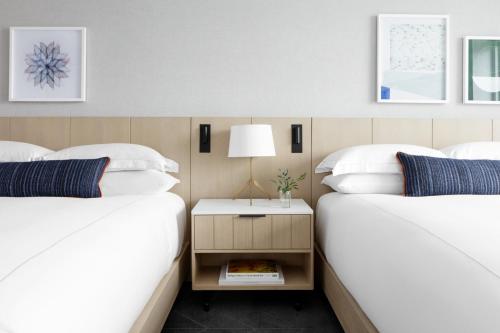 two beds with white sheets and a nightstand between them at Kimpton - The Forum Hotel by IHG in Charlottesville
