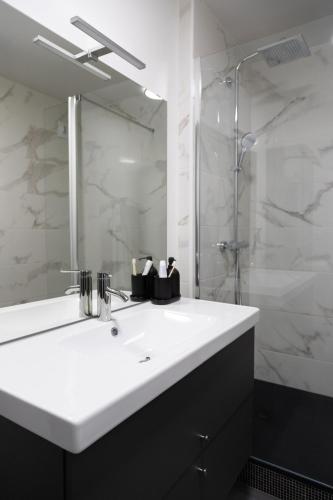 une salle de bain avec un lavabo blanc et une douche dans l'établissement Les Jardins du Pont Rouge - Cosy et Calme, à Aurillac