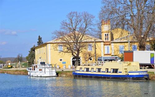 two boats are docked in the water in front of a building at Villa Napoléon Piscine&Jacuzzi in Le Somail